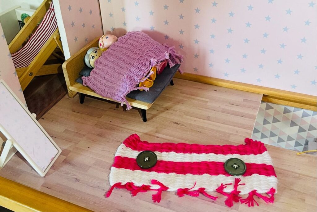 Kind stellt im freien Spiel eine Decke für das Puppenhaus selbst her - freies Lernen im Alltag
