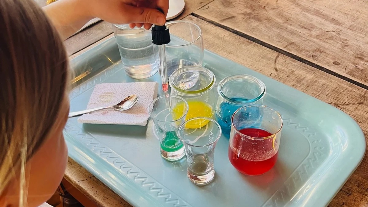 Kind mischt Farben mit Pipette und Gläsern – freies Lernen im Alltag