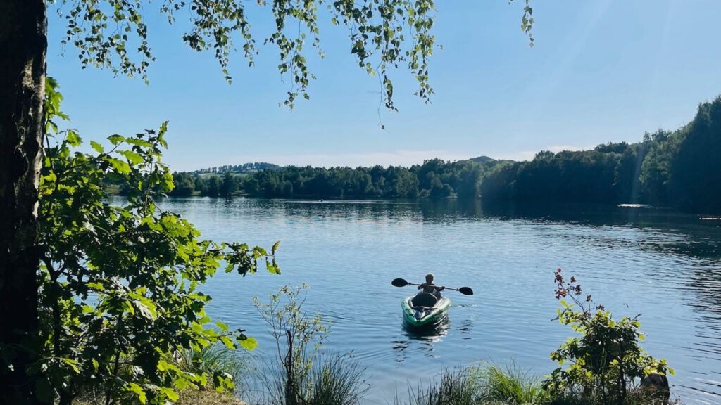 Ein Kind paddelt mit dem Kanu auf einem See - Bewegung im Alltag entsteht bei uns oft ganz natürlich beim Unterwegssein in der Natur.