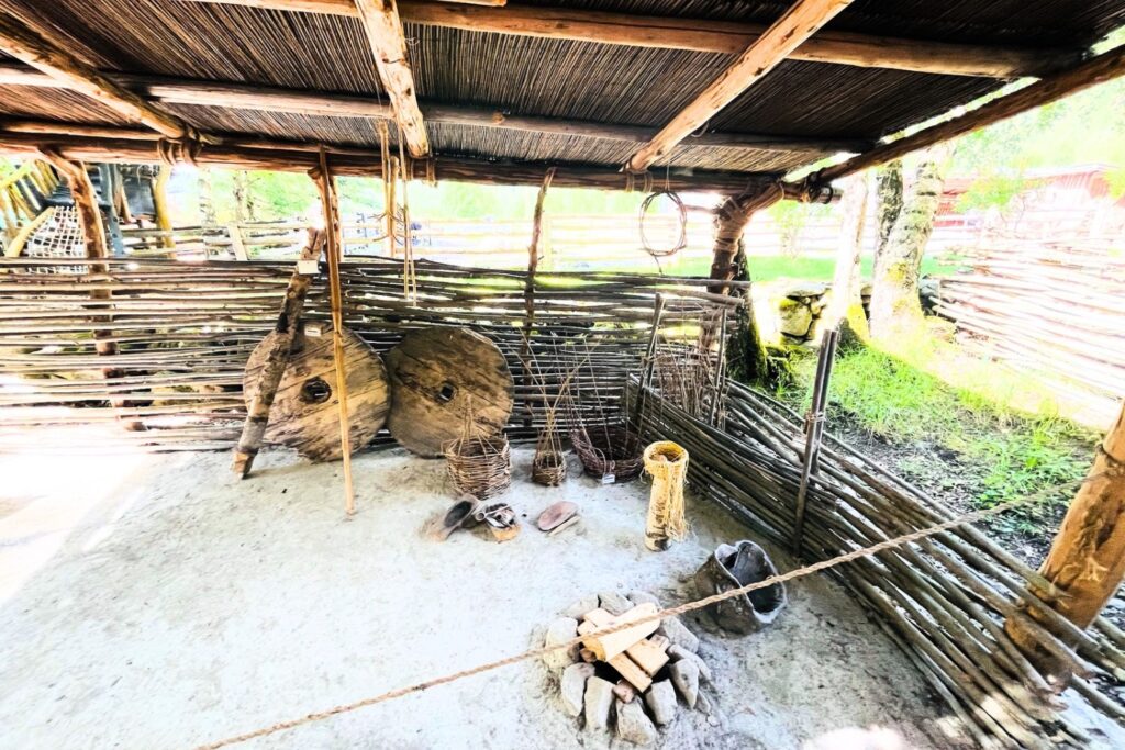Historischer Unterstand im Ötzi-Dorf Umhausen mit Feuerstelle, Flechtwänden und steinzeitlicher Ausstellung.